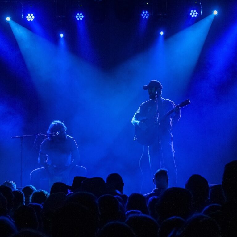 two musicians on stage with dramatic light.
