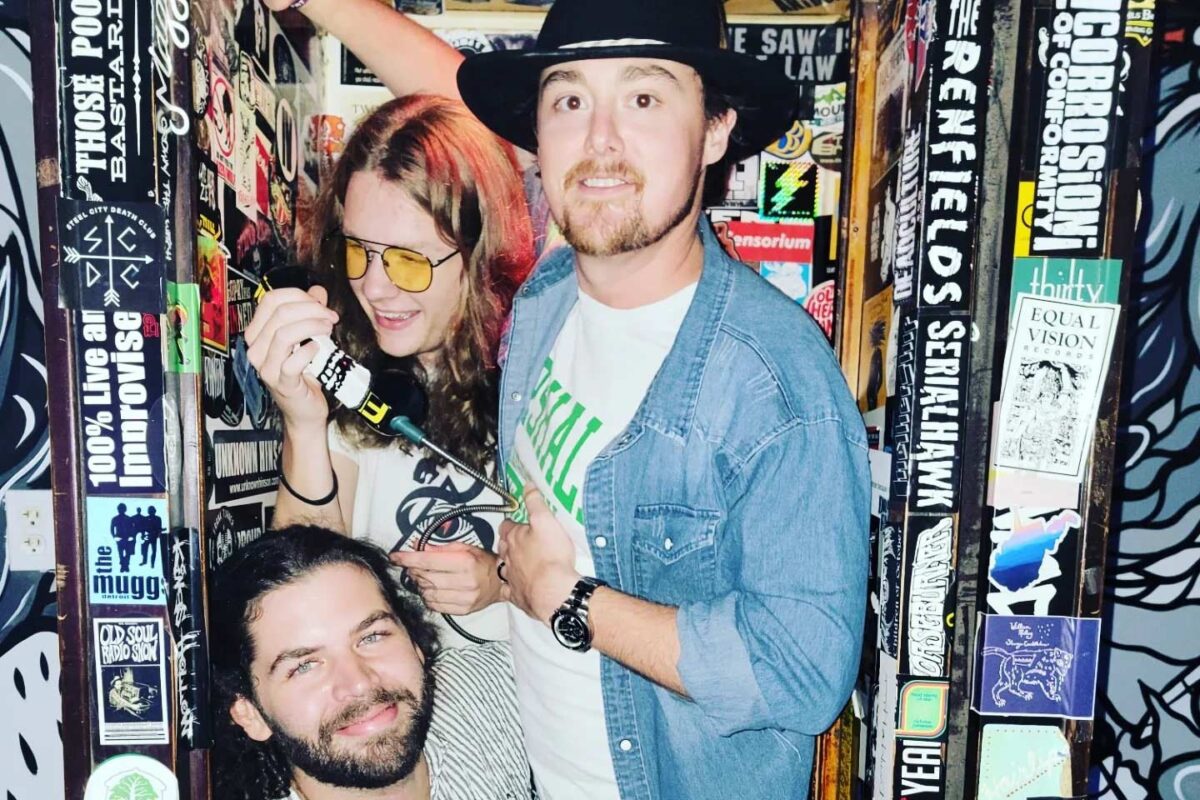 Three people crowded into a small nook with lots of stickers.