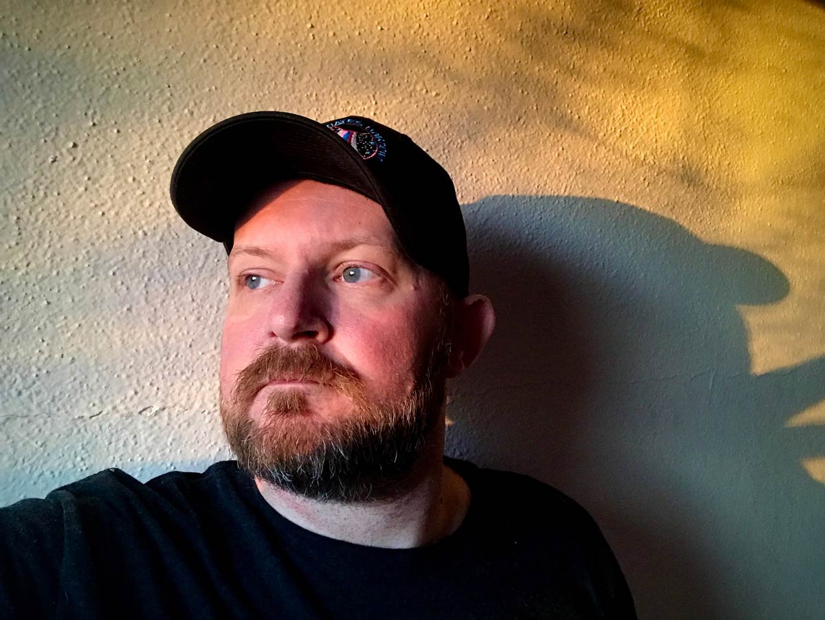 portrait of man with beard and baseball cap in golden natural light