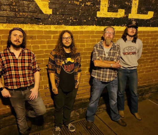 four men standing at brick wall