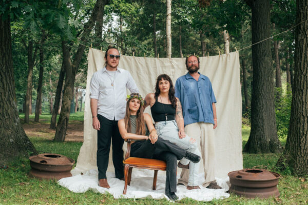 band members posing among trees in front of sheet on clothesline