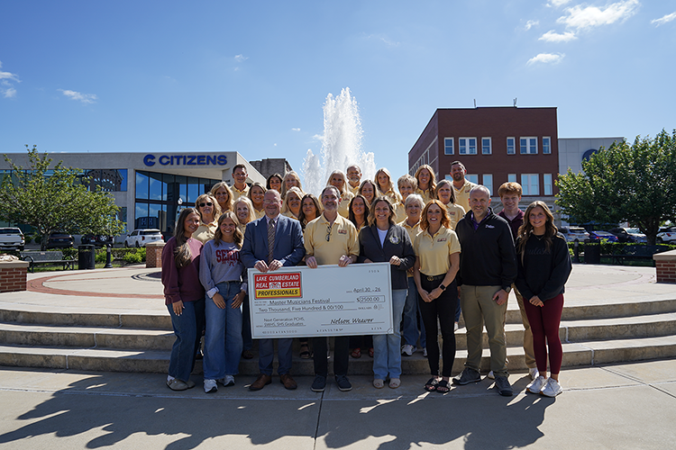 group of people standing on town square holding large donation check sponsoring pulaski graduates festival attendance